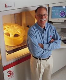 Chuck Hull stands next to a 3d printer